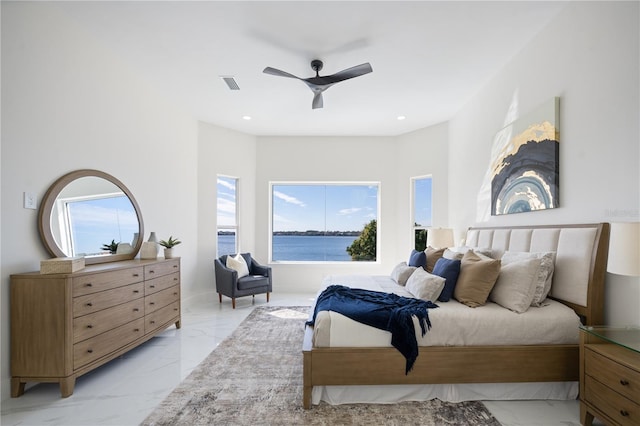 bedroom with multiple windows, ceiling fan, and a water view