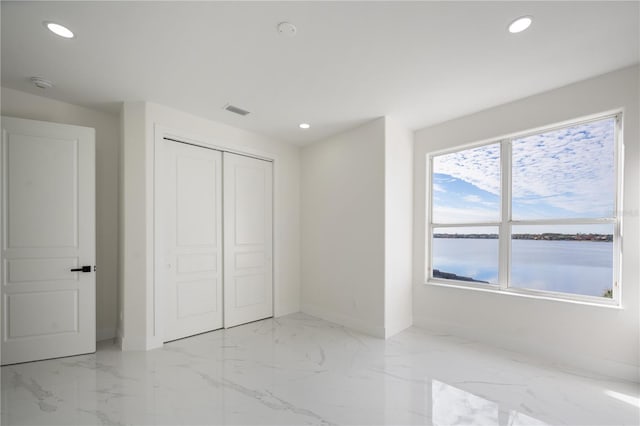 unfurnished bedroom featuring a water view and a closet