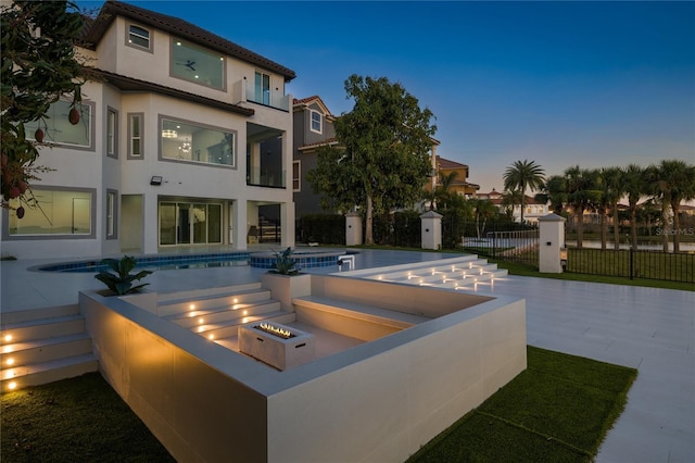 pool at dusk with a hot tub, a patio, and a fire pit