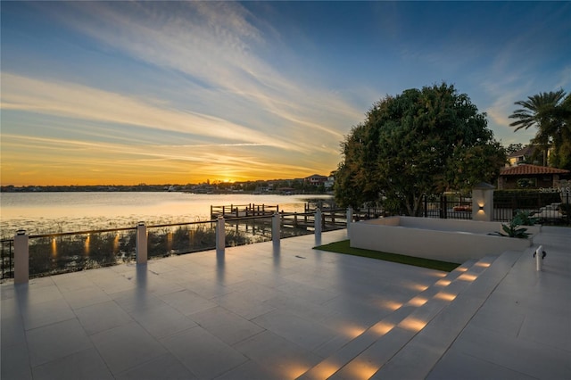 patio terrace at dusk featuring a water view