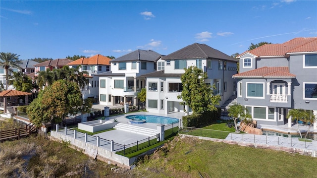 rear view of property with a hot tub and a lawn