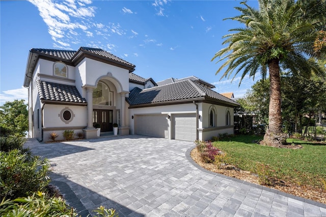 mediterranean / spanish home with a garage and a front lawn