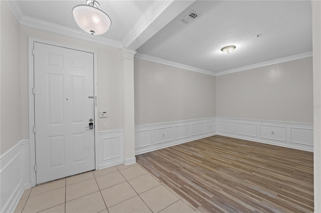 tiled entrance foyer featuring a textured ceiling and ornamental molding