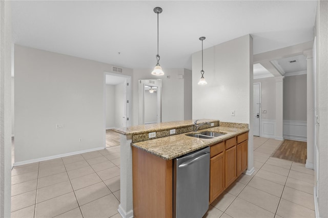 kitchen with light stone countertops, light tile patterned floors, sink, decorative light fixtures, and stainless steel dishwasher