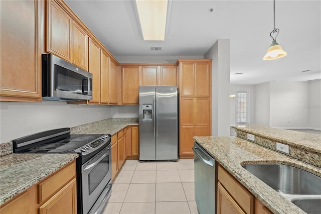 kitchen with light stone counters, pendant lighting, stainless steel appliances, light tile patterned floors, and sink