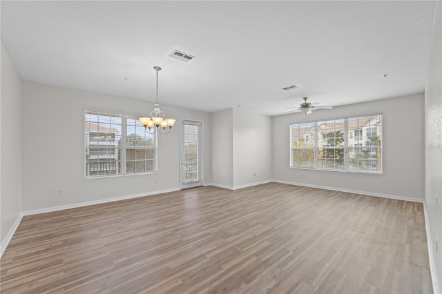 spare room featuring ceiling fan with notable chandelier and light wood-type flooring