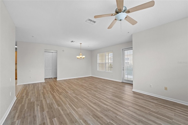 empty room featuring ceiling fan with notable chandelier and light hardwood / wood-style flooring