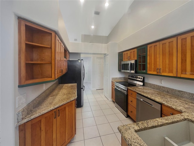 kitchen featuring vaulted ceiling, appliances with stainless steel finishes, and light stone counters