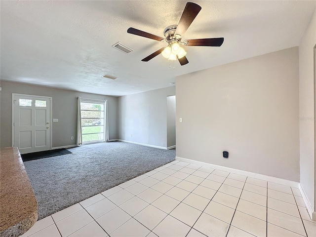 unfurnished room featuring ceiling fan, light colored carpet, and a textured ceiling