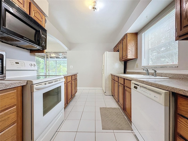 kitchen featuring sink, white appliances, light tile patterned floors, and a healthy amount of sunlight