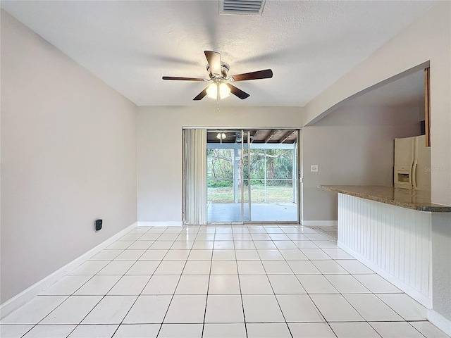 empty room with a textured ceiling, ceiling fan, and light tile patterned flooring