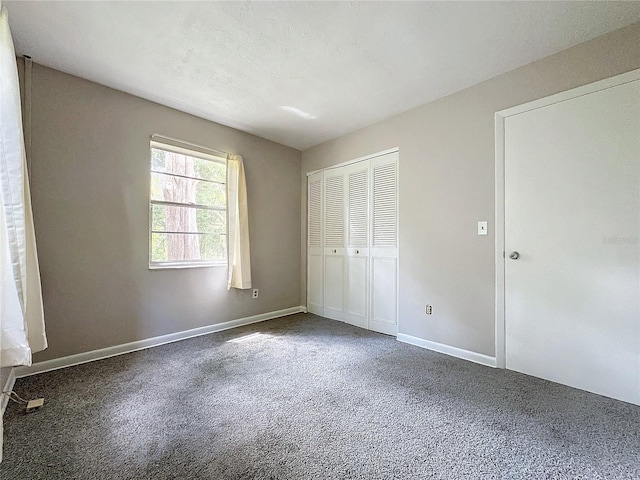 unfurnished bedroom featuring a closet and dark colored carpet