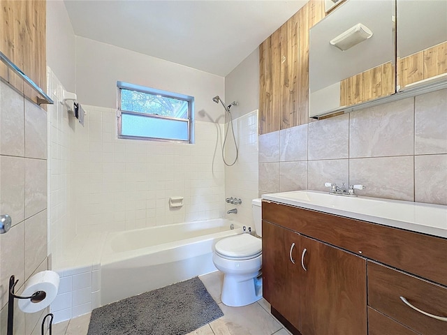 full bathroom featuring tiled shower / bath, tile patterned floors, vanity, tile walls, and toilet