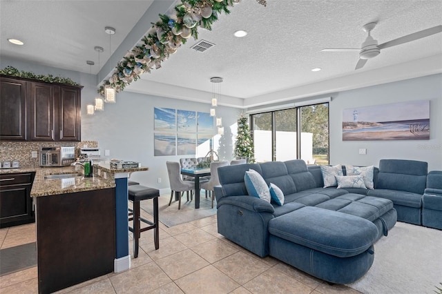 tiled living room featuring ceiling fan and a textured ceiling