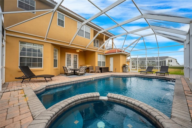 view of pool with grilling area, glass enclosure, a patio area, an outdoor hangout area, and an in ground hot tub