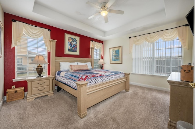 carpeted bedroom featuring ceiling fan and a tray ceiling