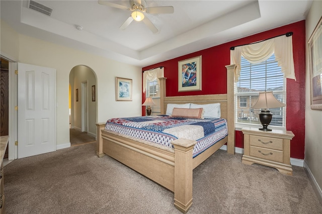 bedroom with a raised ceiling, ceiling fan, and carpet flooring