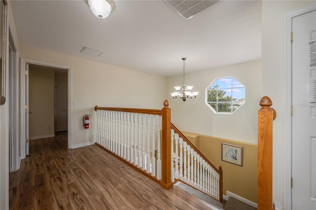 hallway with dark hardwood / wood-style flooring and an inviting chandelier