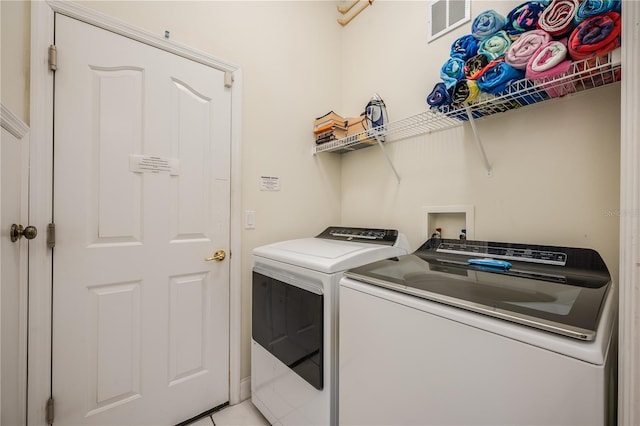 clothes washing area featuring light tile patterned floors and independent washer and dryer