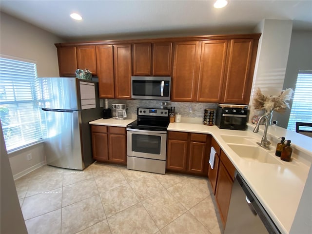 kitchen featuring light tile patterned floors, sink, backsplash, and appliances with stainless steel finishes