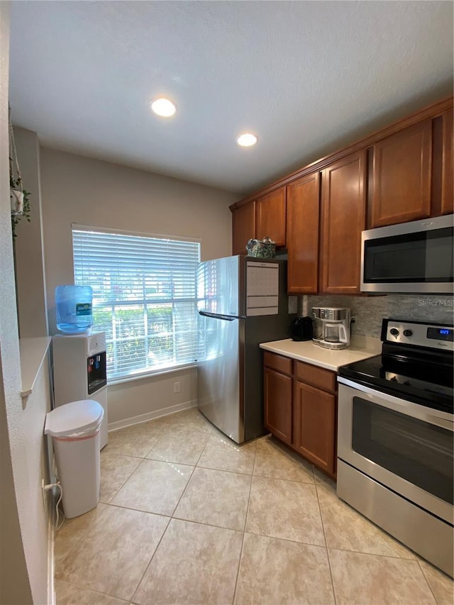 kitchen with light tile patterned floors, washer / clothes dryer, and stainless steel appliances