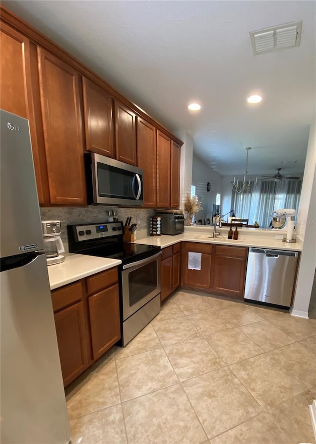 kitchen featuring pendant lighting, sink, light tile patterned flooring, appliances with stainless steel finishes, and ceiling fan with notable chandelier