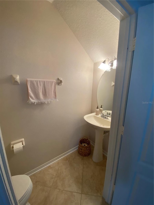 bathroom with toilet, a textured ceiling, lofted ceiling, and tile patterned floors