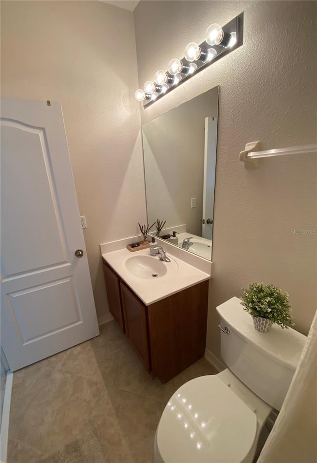 bathroom with toilet, tile patterned flooring, and vanity