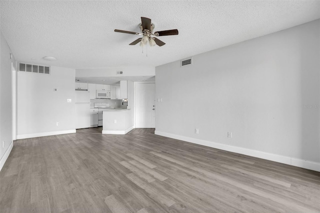 unfurnished living room featuring ceiling fan, a textured ceiling, and light hardwood / wood-style floors