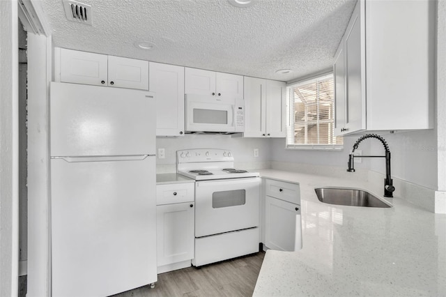 kitchen with sink, white appliances, light hardwood / wood-style flooring, white cabinetry, and a textured ceiling