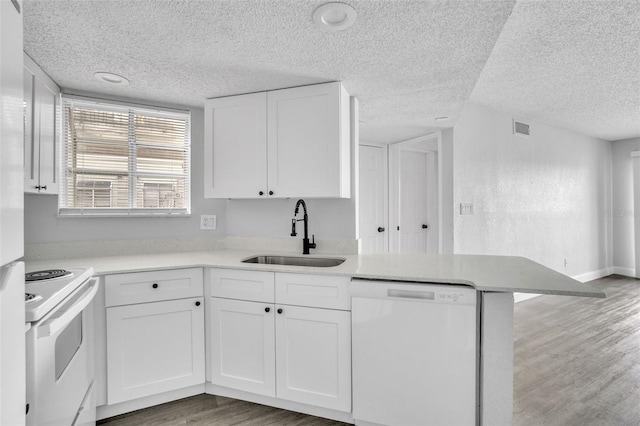 kitchen featuring sink, white appliances, white cabinetry, wood-type flooring, and kitchen peninsula