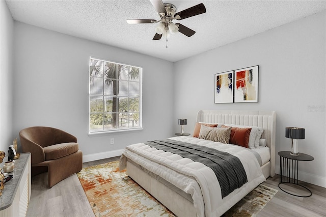 bedroom with ceiling fan, hardwood / wood-style floors, and a textured ceiling