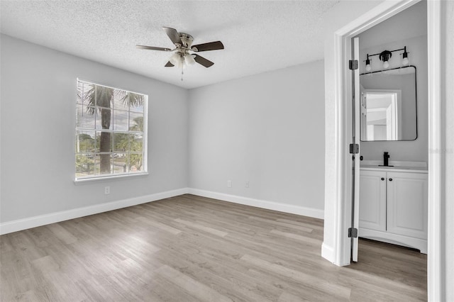 empty room with ceiling fan, light hardwood / wood-style floors, and a textured ceiling