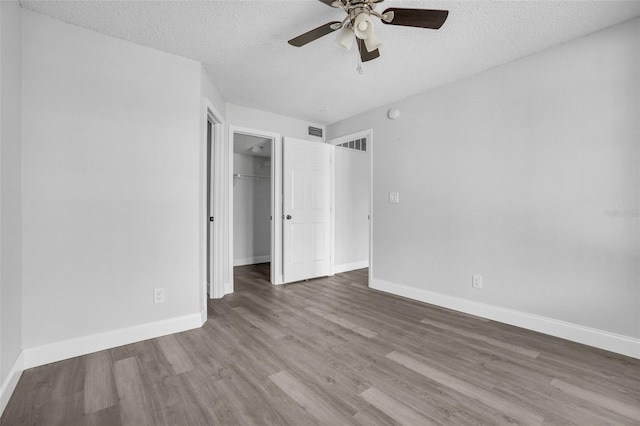 unfurnished bedroom with ceiling fan, a closet, wood-type flooring, and a textured ceiling