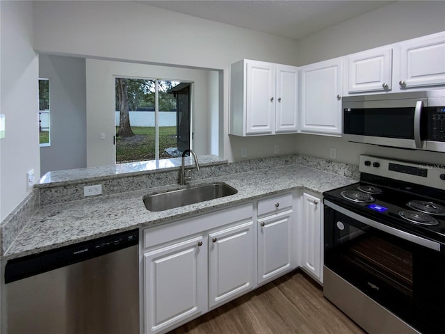 kitchen with light stone counters, dark hardwood / wood-style flooring, white cabinets, appliances with stainless steel finishes, and sink