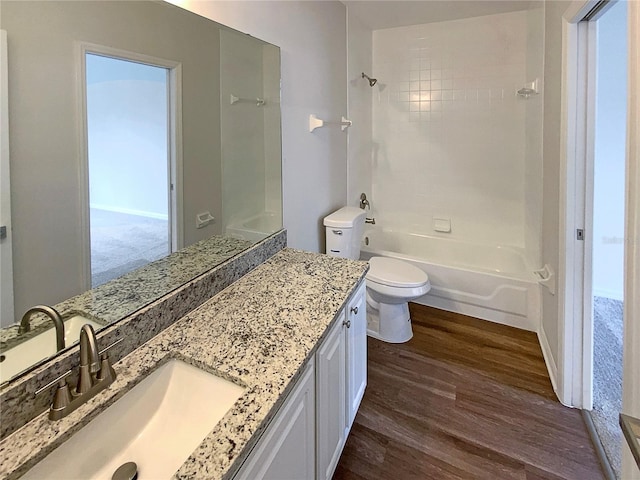 full bathroom with toilet, hardwood / wood-style flooring, tiled shower / bath, and vanity