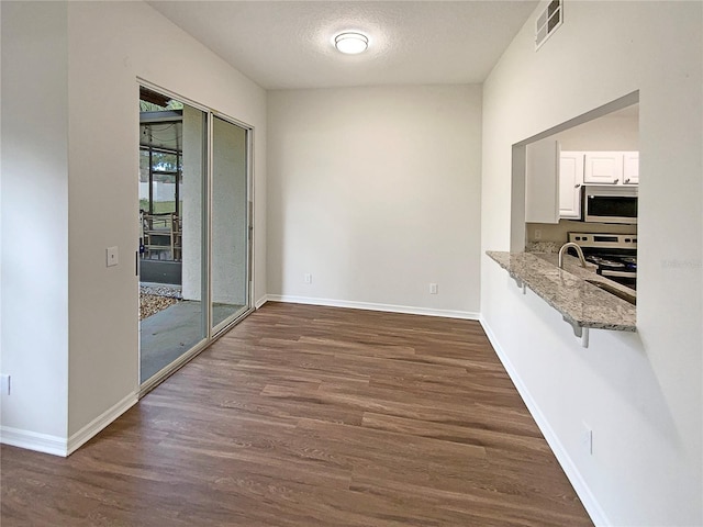 unfurnished dining area featuring a textured ceiling, plenty of natural light, and dark wood-type flooring