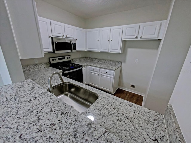 kitchen featuring sink, range with electric cooktop, white cabinetry, and light stone counters