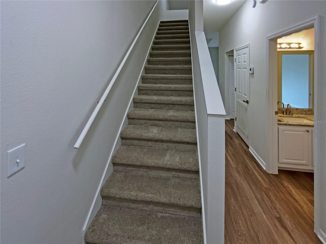 stairs featuring wood-type flooring and sink