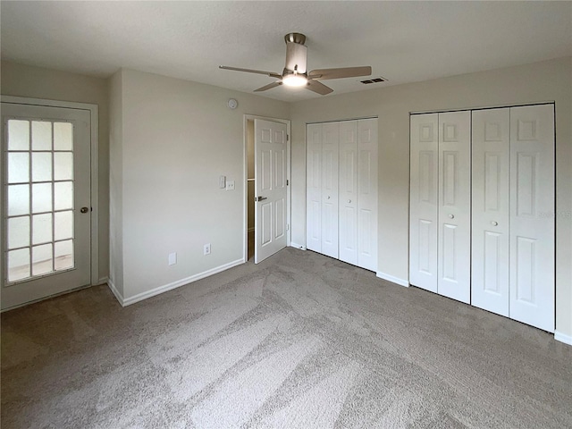 unfurnished bedroom with carpet flooring, two closets, and ceiling fan