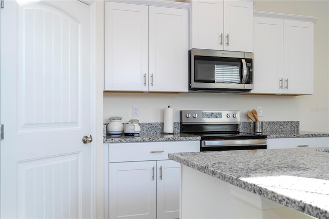 kitchen with light stone countertops, white cabinets, and appliances with stainless steel finishes