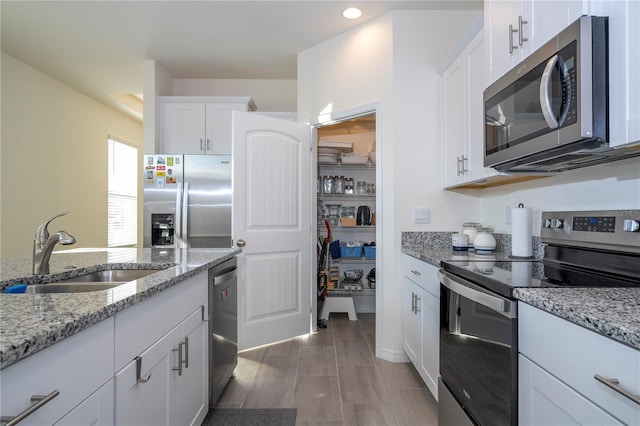 kitchen with sink, stainless steel appliances, white cabinets, and light stone counters