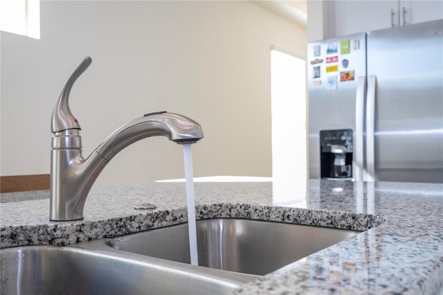 details with light stone counters, stainless steel fridge with ice dispenser, and sink