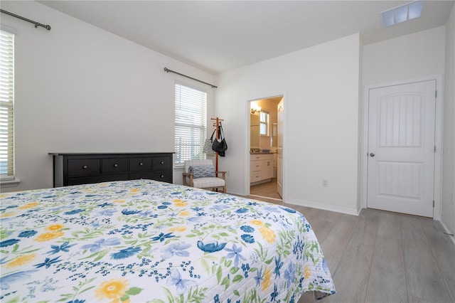 bedroom featuring ensuite bath and light wood-type flooring