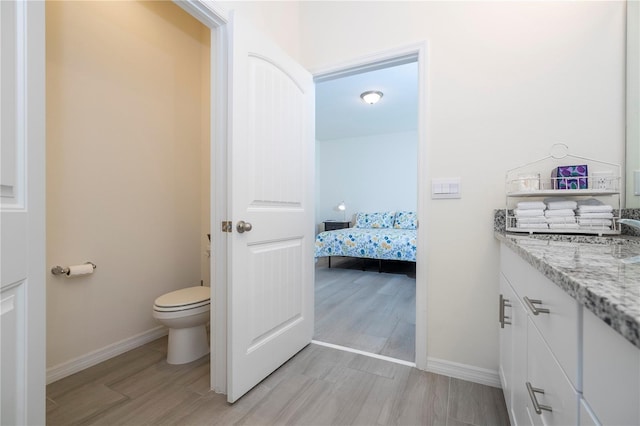 bathroom with toilet, hardwood / wood-style flooring, and vanity