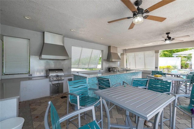 view of patio with an outdoor kitchen, ceiling fan, exterior bar, and a grill