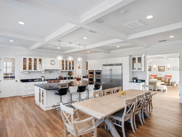 dining area featuring beamed ceiling, coffered ceiling, and light hardwood / wood-style floors