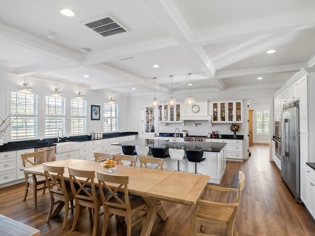 dining area featuring beam ceiling, sink, dark hardwood / wood-style floors, crown molding, and coffered ceiling