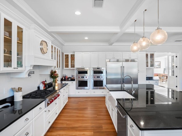 kitchen with beam ceiling, sink, white cabinetry, hanging light fixtures, and appliances with stainless steel finishes