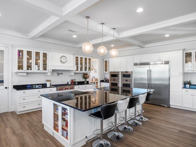 kitchen featuring pendant lighting, a breakfast bar, beamed ceiling, an island with sink, and stainless steel appliances